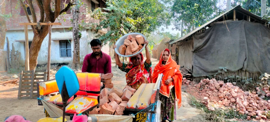 নিজে ঘাড়ে করে ইট বহন করে নিজ হাতে রাস্তায় বিছিয়ে দেন মেম্বার রেখা