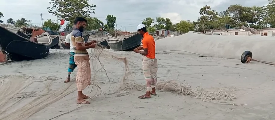 আড়ত ঘাটে জাল সেলাই করছেন জেলেরা