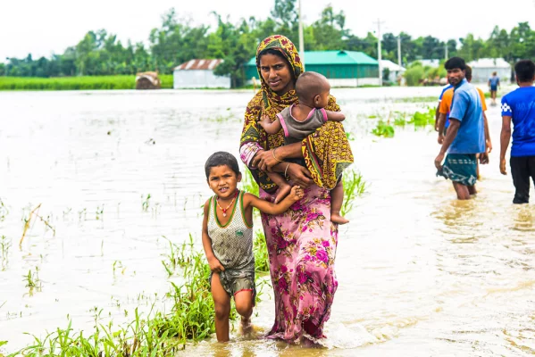 বাড়ি-ঘরে পানি ওঠায় শিশু দুটিকে নিয়ে নিরাপদ ও উঁচু স্থানে নিয়ে যাচ্ছেন মা। মর্ণেয়া ইউনিয়নের আলফাজটারী থেকে তোলা। ছবি: আজকের পত্রিকা