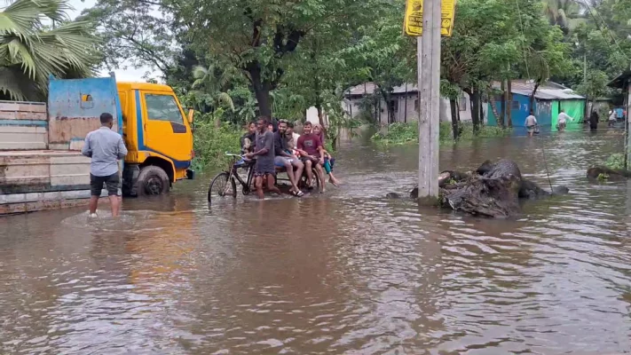 লক্ষ্মীপুরে বন্যার পানিতে ডুবে যাওয়া রাস্তা দিয়ে ভ্যানে চেপে যাচ্ছেন কিছু মানুষ। ছবি: আজকের পত্রিকা