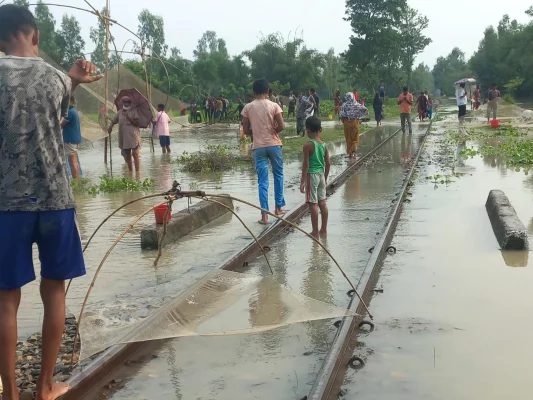 রেললাইনের ওপর দিয়ে বয়ে যাচ্ছে পানি। সেখানে মাছ ধরছে গ্রামবাসী। ছবি: আজকের পত্রিকা